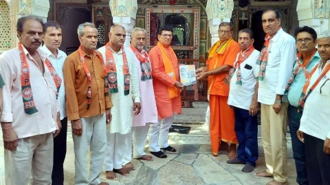 ढूकिया ने पुजारी को पुस्तक भेंट कर सम्पर्क से समर्थन अभियान का किया शुभारम्भ किया